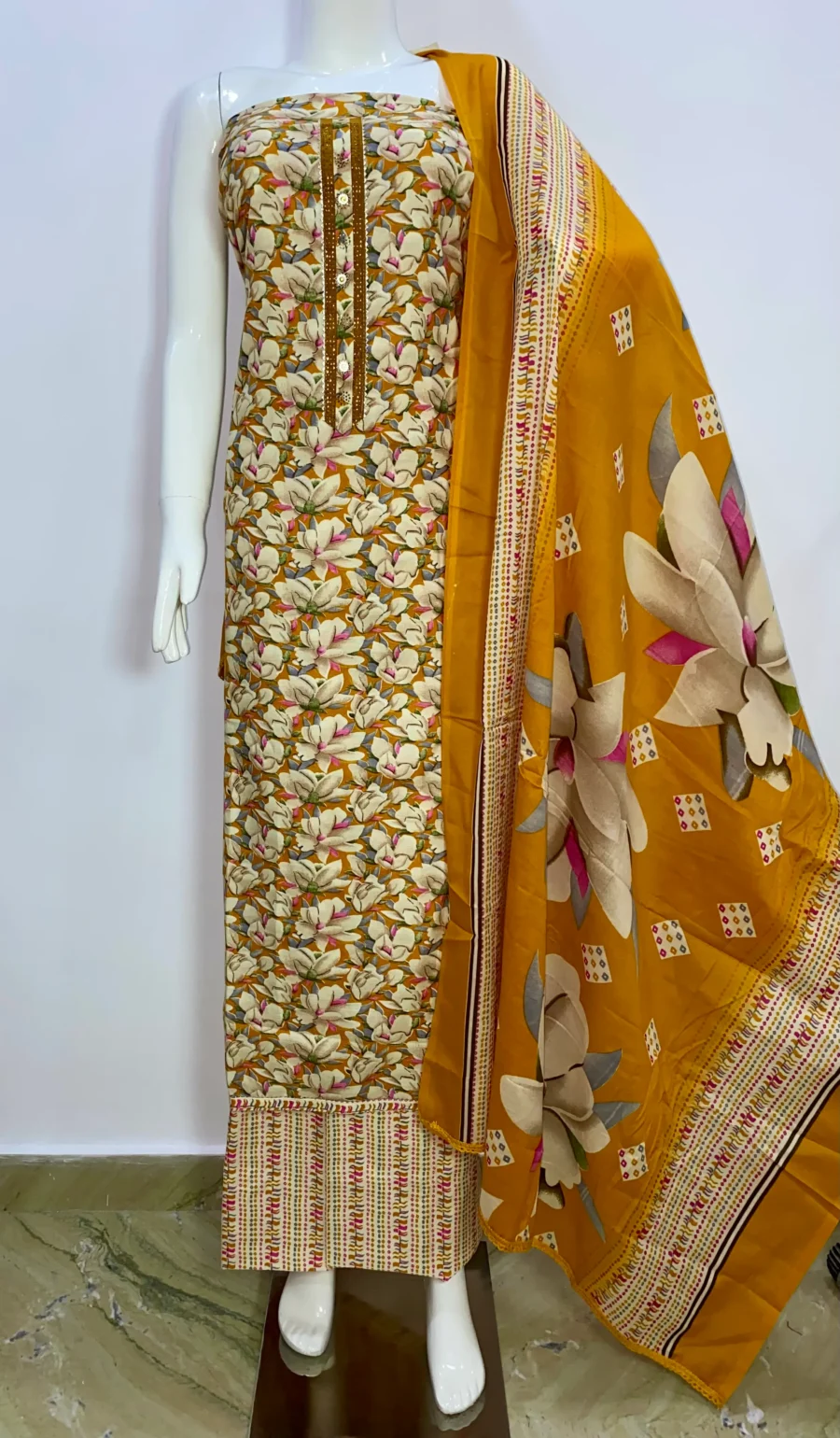 Unstitched Golden Yellow floral print cotton suit with printed muslin dupatta displayed on mannequin – ethnic wear by Sardarniz Fashion